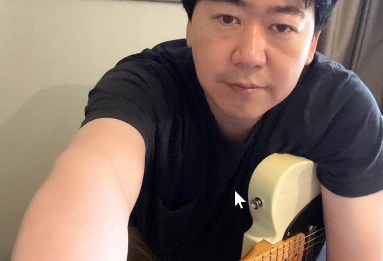 A man is holding a guitar and looking forward.